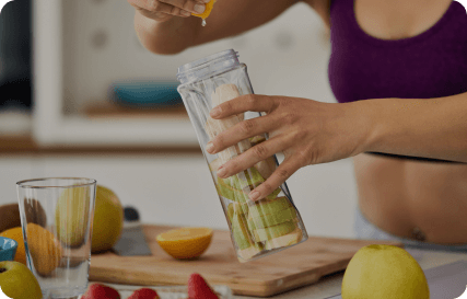 A woman makes a smoothie and squeezes lemon into a glass bottle